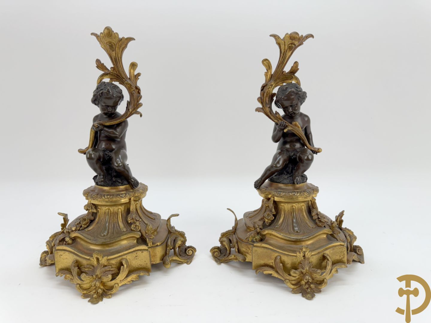 Driedelige bronzen garnituur bestaande uit middenstuk met bronzen vuurvergulde klok, Daubrée gemerkt à Nancy, bovenaan bekroond met Cleopatra met drinkbeker - getekend van Cumberworth sculpteur - geflankeerd door paar cupido