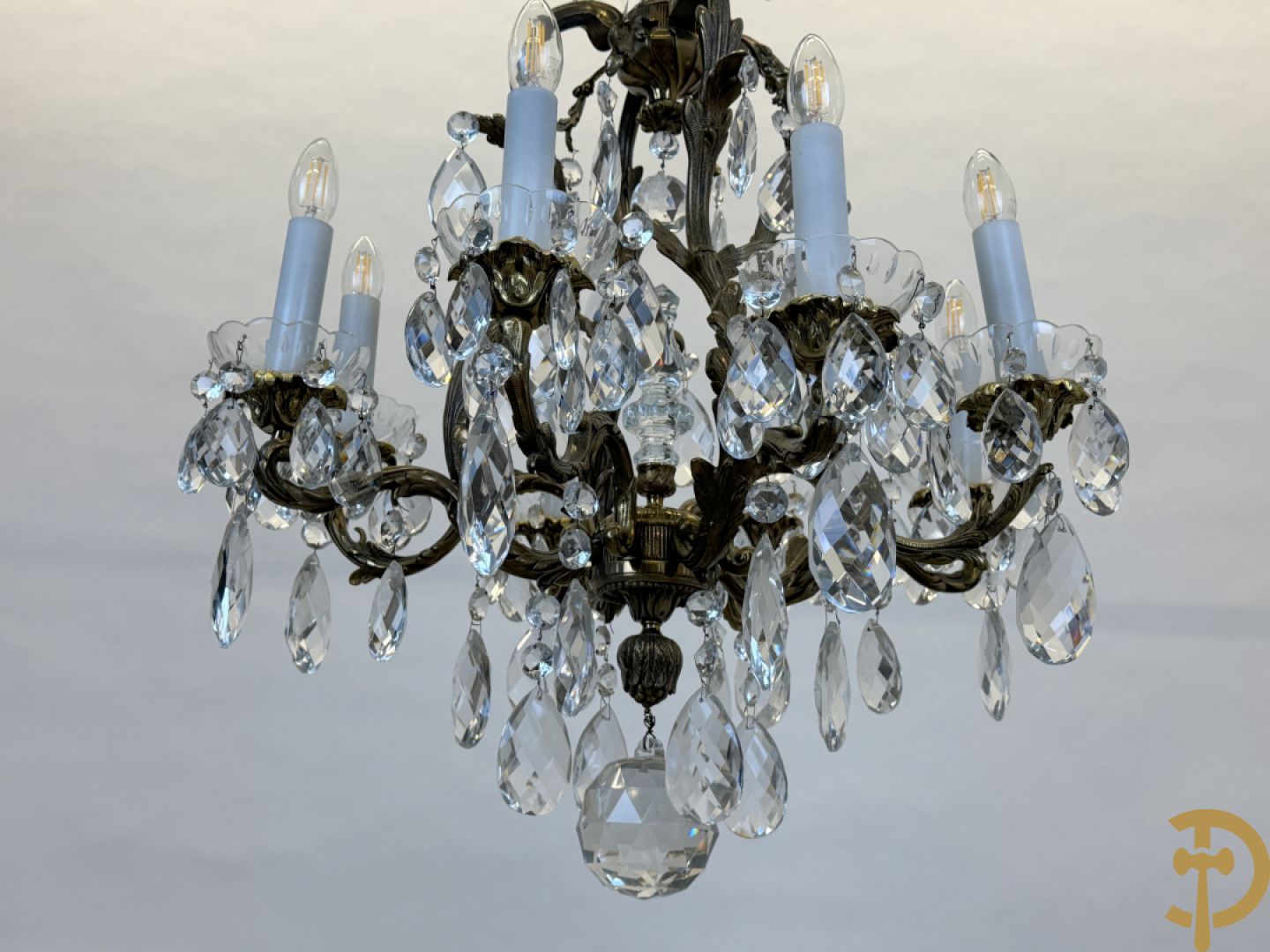 Achtarmige koperen luchter met kristallen bellen en binnenin met pinakel bezet