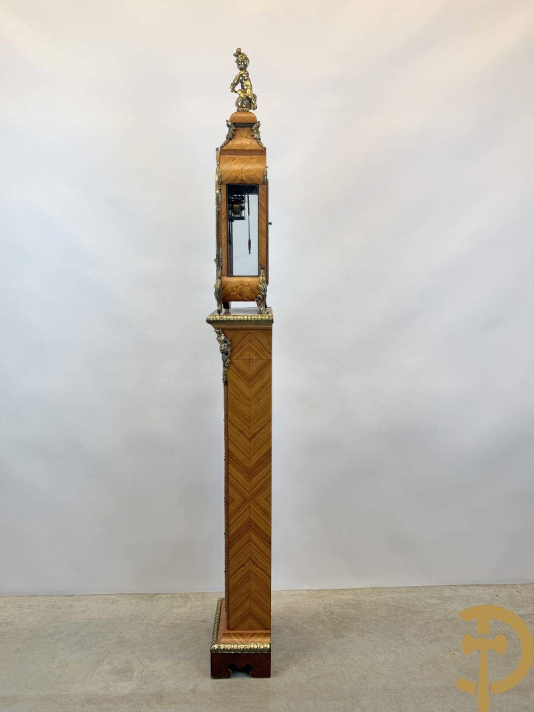 Notelaren pendule met bloemenmarquetterie en bronsbeslag, bovenaan bekroond met bronzen figuur - met bijhorende sokkel in notelaar met bronsbeslag