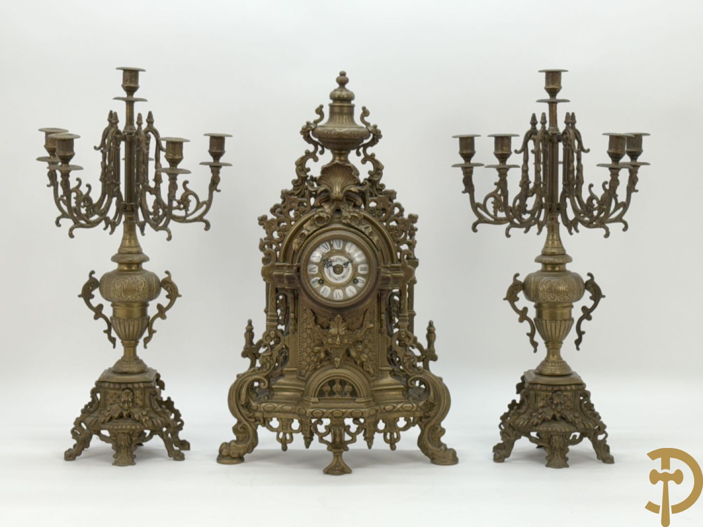 Driedelige koperen garnituur, klok geflankeerd door paar vijfarmige kandelaars