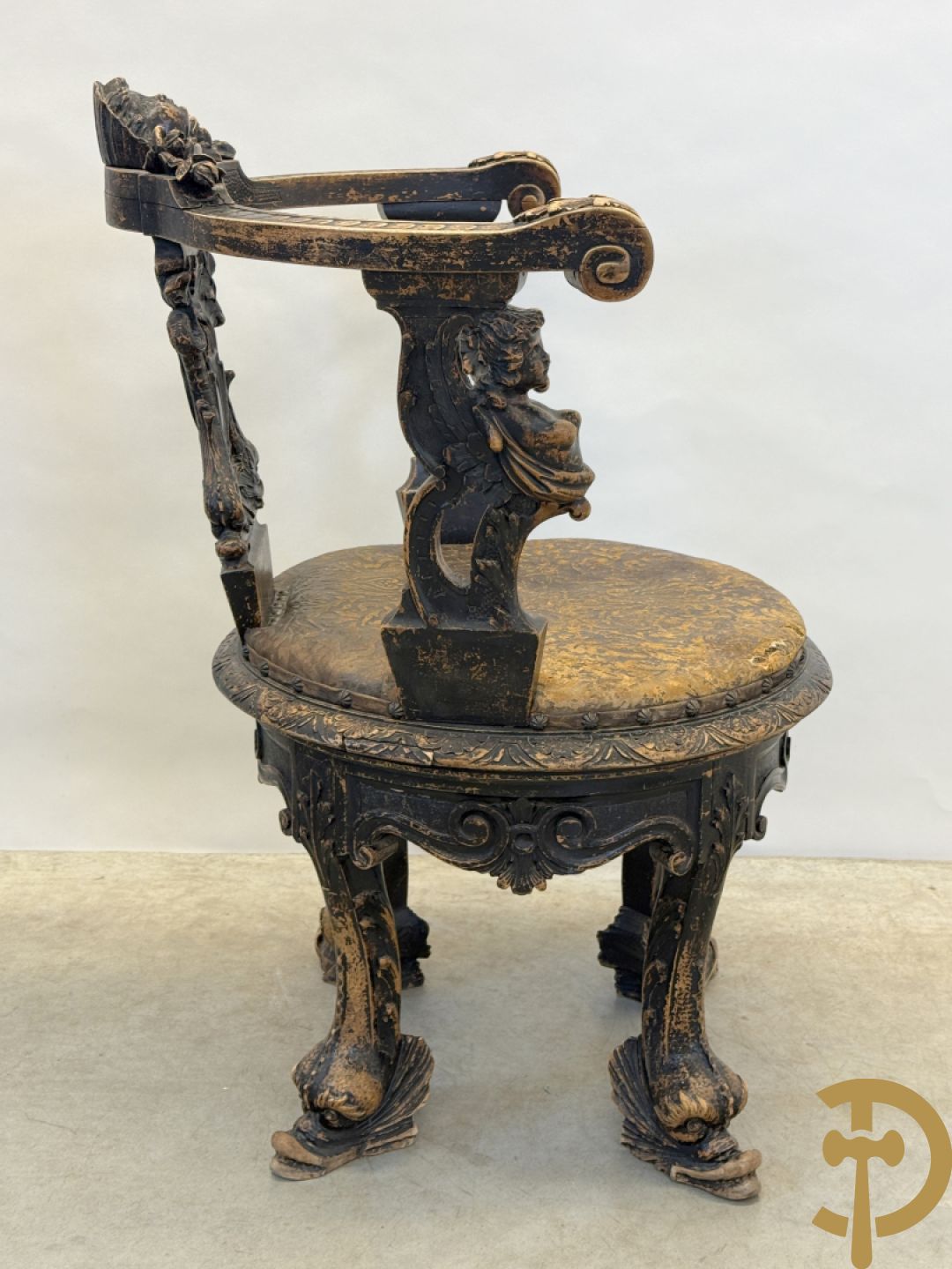 Gesculpteerde draaibare gondelvormige stoel steunend op 4 poten in de vorm van dolfijnen, bovenaan met kariathiden en engelenkoppen