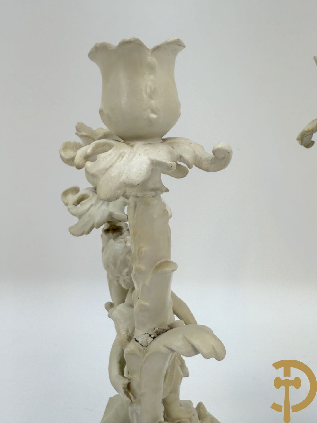 Driedelige porseleinen garnituur bestaande uit pendule bezet met lieftallig koppel, geflankeerd door paar kandelaars met cupido