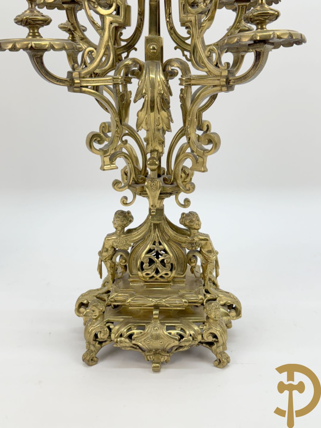 Driedelige bronzen vergulde garntiuur bestaande uit klok met medusahoofden en sfinxen, geflankeerd door paar zevenarmige kandelaars met accanthusranken en sfinxen