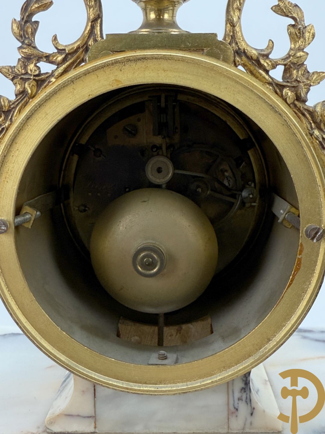 Driedelige wit marmeren garnituur bestaande uit vierzuilenpendule met bloemen en troffee geflankeerd door paar cassolettes met ramskoppen bezet