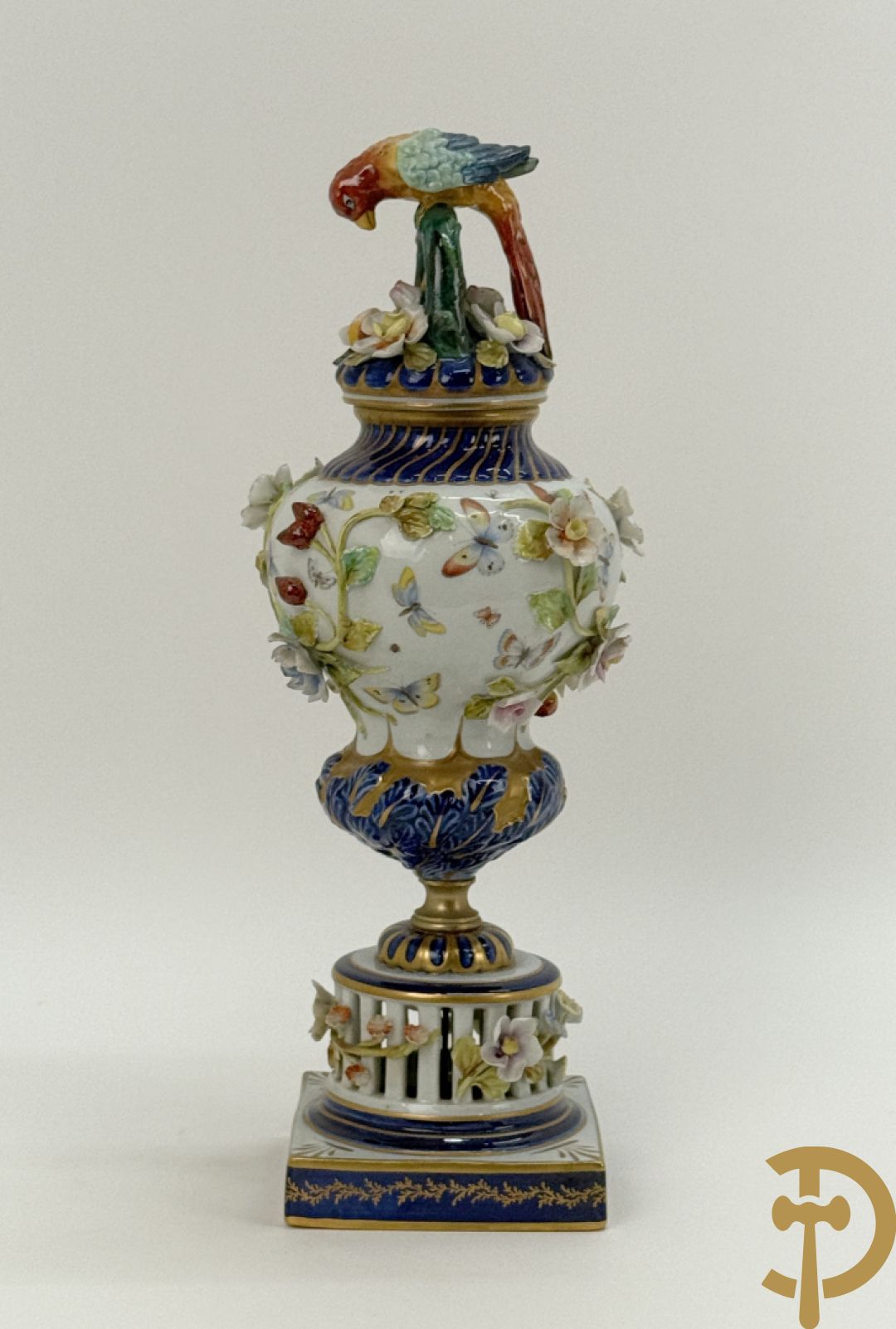 Porseleinen siervaas met handbeschilderd geanimeerd decor bezet met basrelief van bloemen en bovenaan bekroond met deksel met vogel