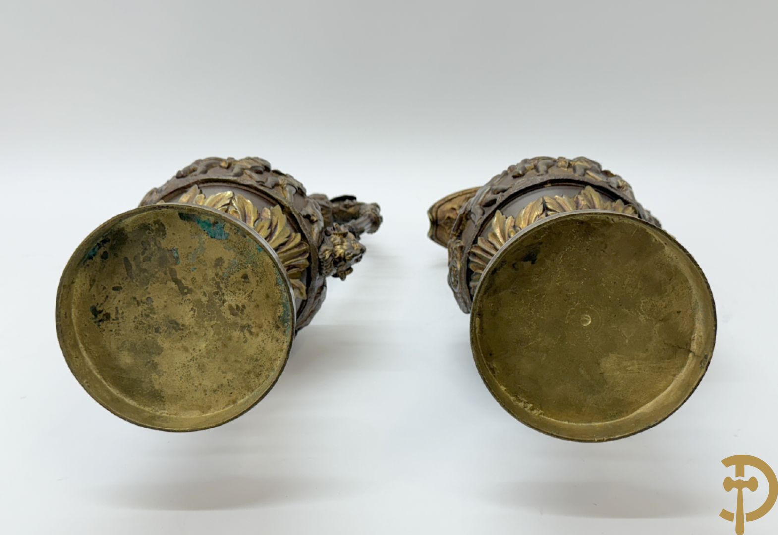 Paar bronzen schenkkannen met basrelief van putti en accanthusranken