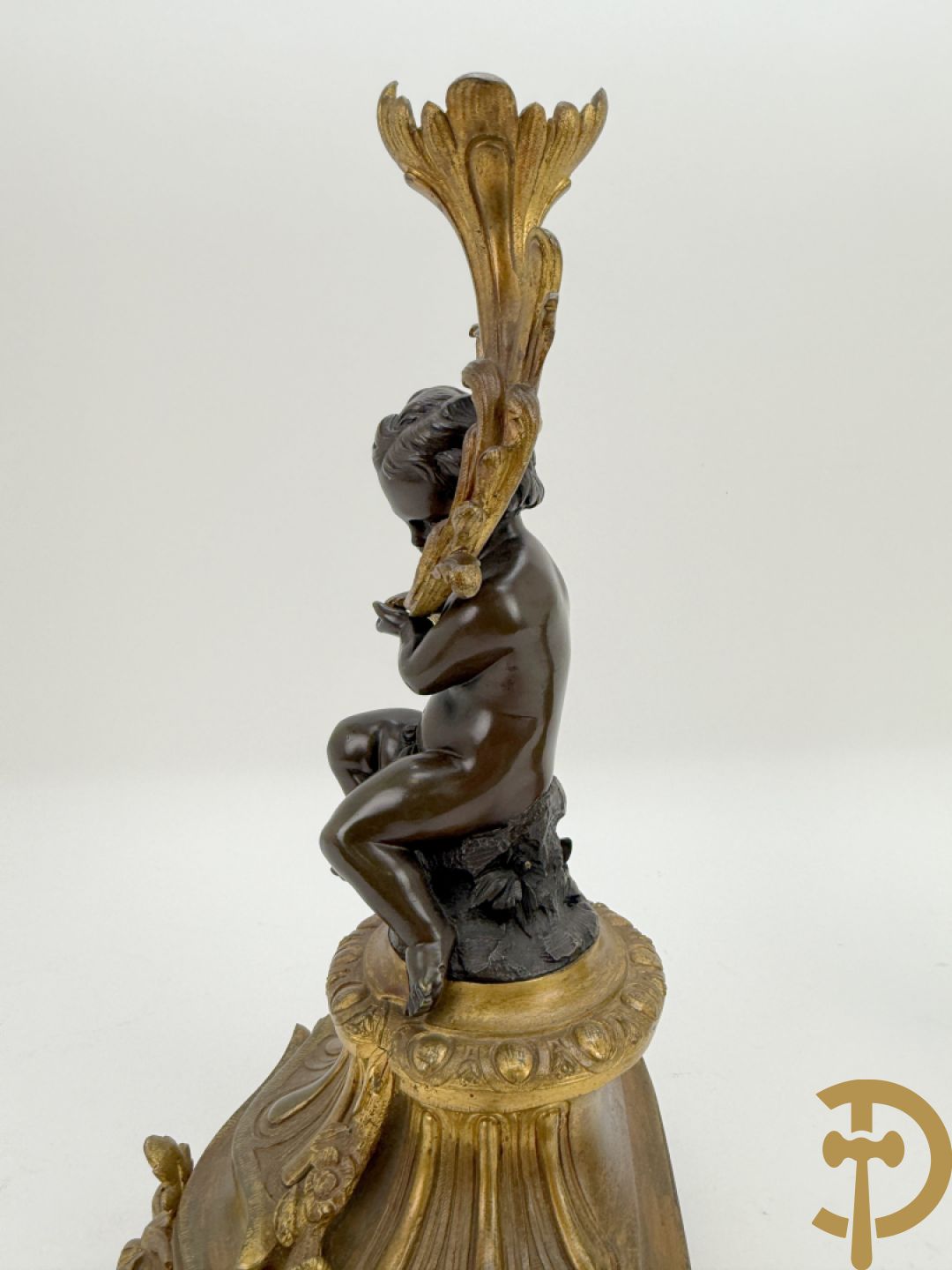 Driedelige bronzen garnituur bestaande uit middenstuk met bronzen vuurvergulde klok, Daubrée gemerkt à Nancy, bovenaan bekroond met Cleopatra met drinkbeker - getekend van Cumberworth sculpteur - geflankeerd door paar cupido