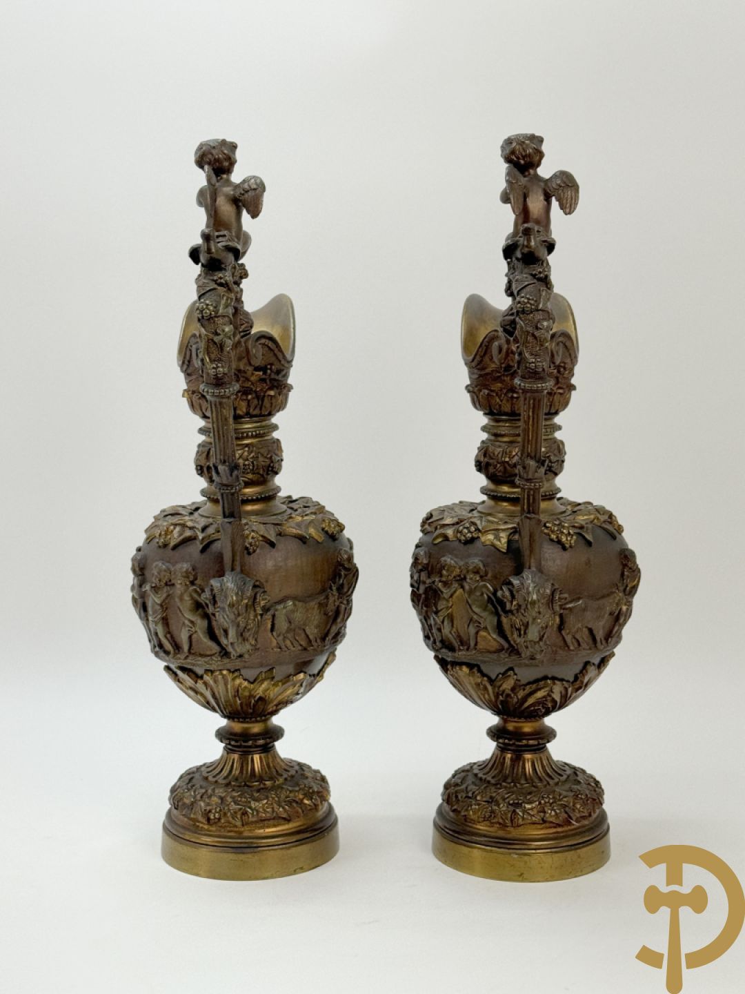 Paar bronzen schenkkannen met basrelief van putti en accanthusranken