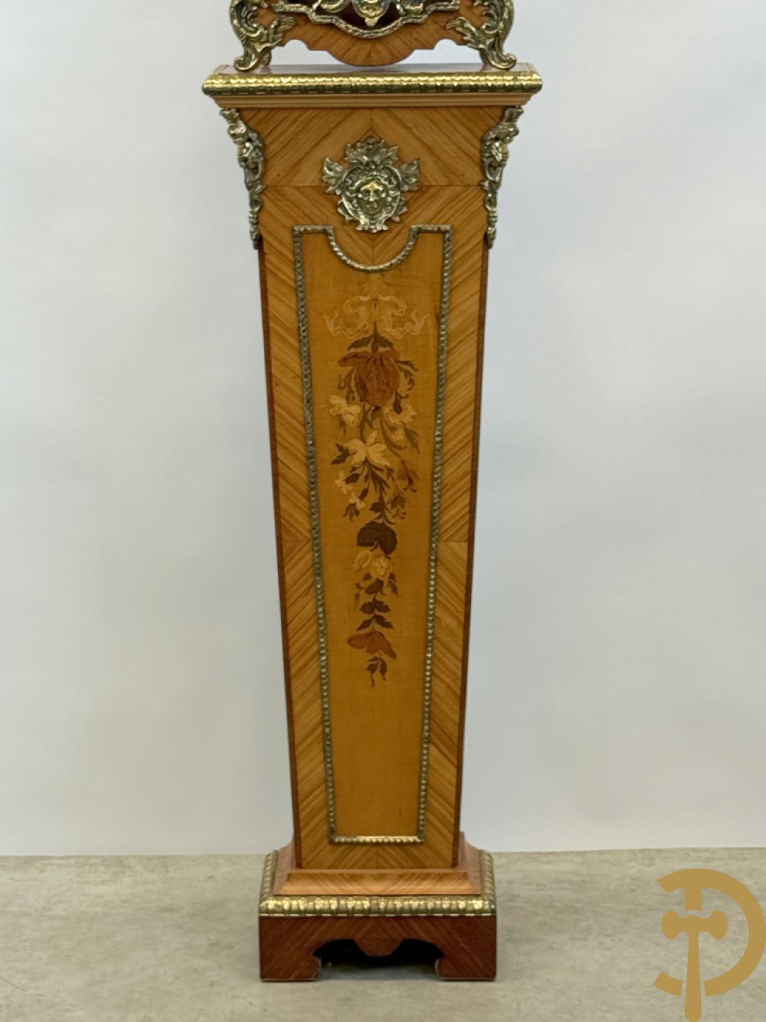 Notelaren pendule met bloemenmarquetterie en bronsbeslag, bovenaan bekroond met bronzen figuur - met bijhorende sokkel in notelaar met bronsbeslag