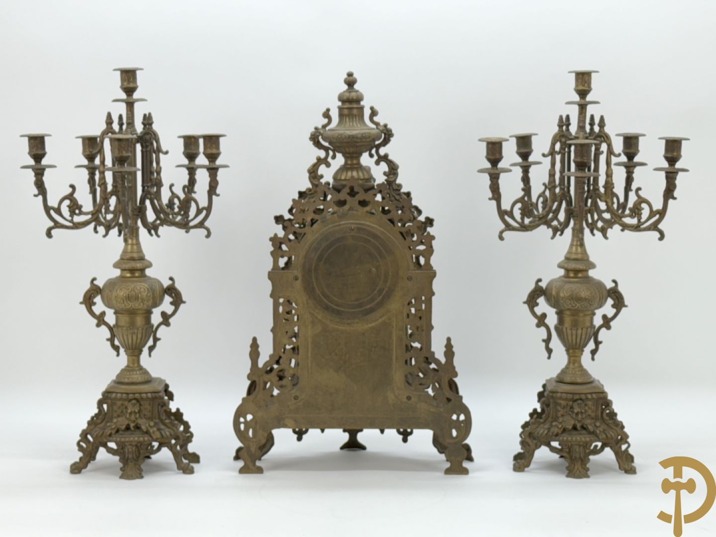 Driedelige koperen garnituur, klok geflankeerd door paar vijfarmige kandelaars