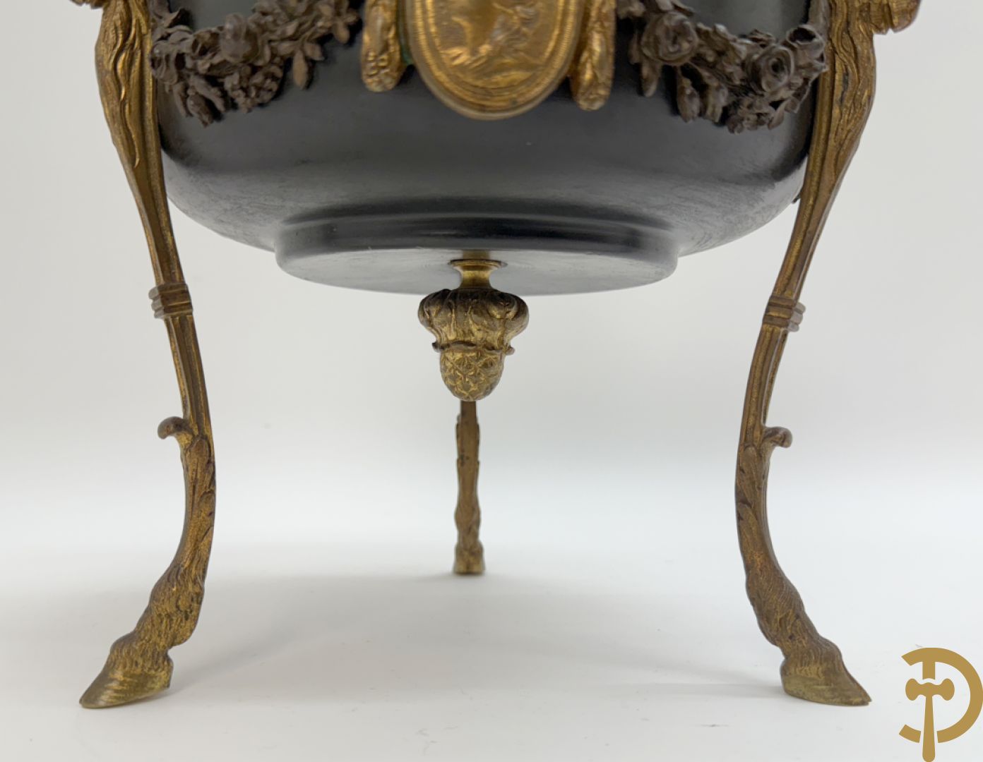 Bronzen coupe op 3 bokkepoten met ramskoppen  bezet en verbonden door guirlandes met medaillon