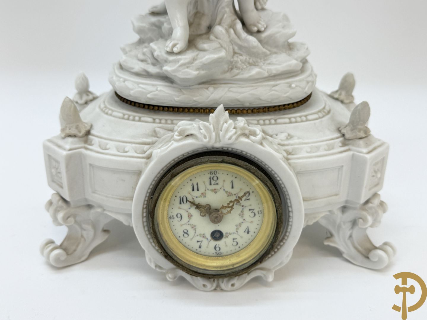 Driedelige porseleinen garnituur bestaande uit pendule bezet met lieftallig koppel, geflankeerd door paar kandelaars met cupido