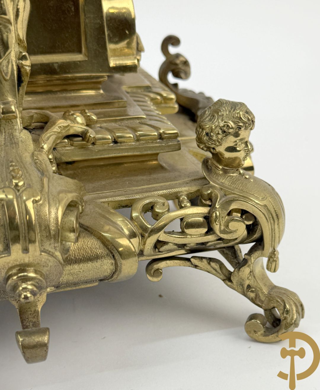 Driedelige bronzen vergulde garntiuur bestaande uit klok met medusahoofden en sfinxen, geflankeerd door paar zevenarmige kandelaars met accanthusranken en sfinxen