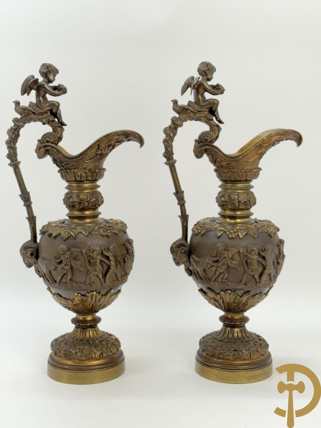 Paar bronzen schenkkannen met basrelief van putti en accanthusranken