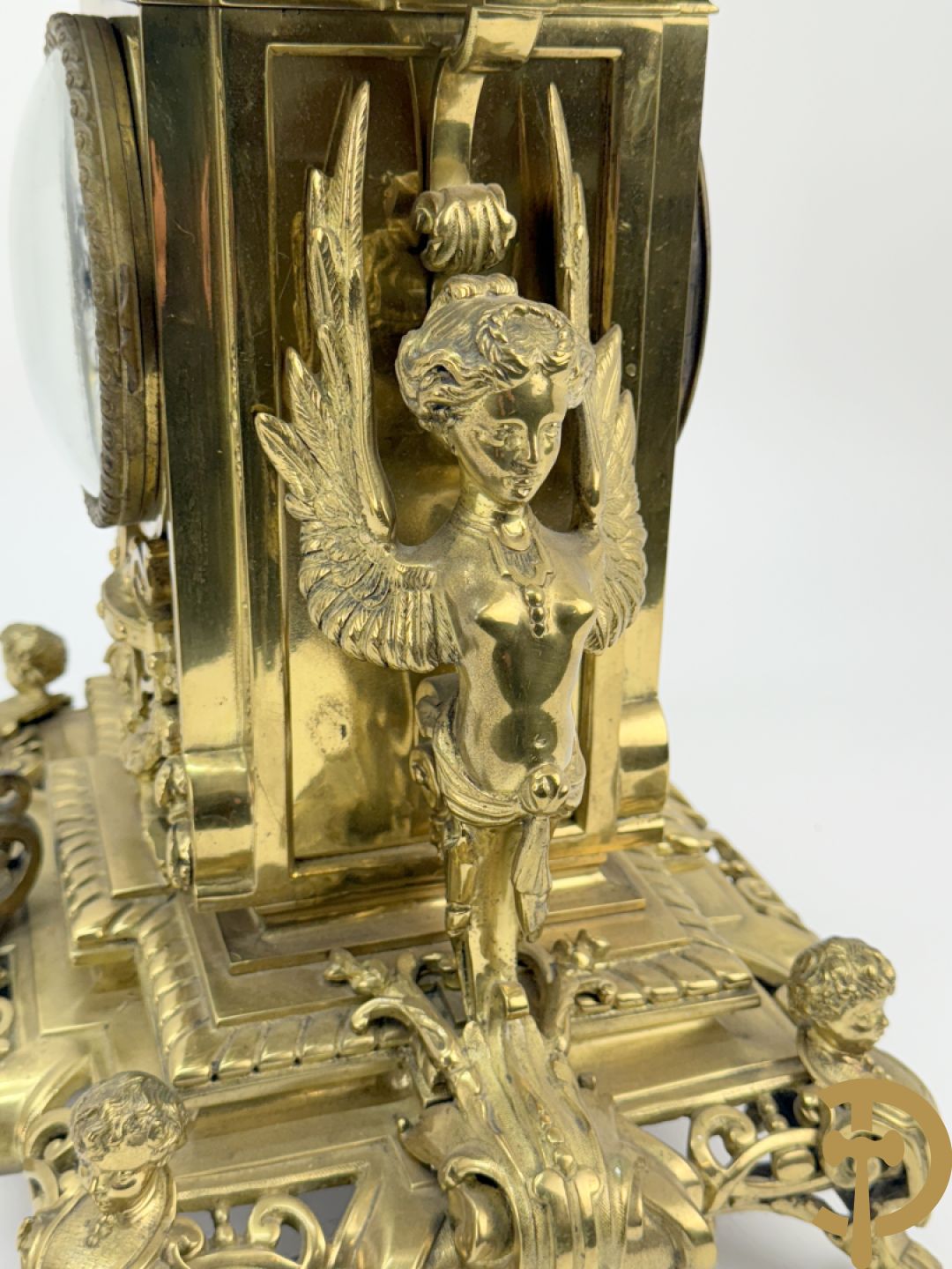 Driedelige bronzen vergulde garntiuur bestaande uit klok met medusahoofden en sfinxen, geflankeerd door paar zevenarmige kandelaars met accanthusranken en sfinxen