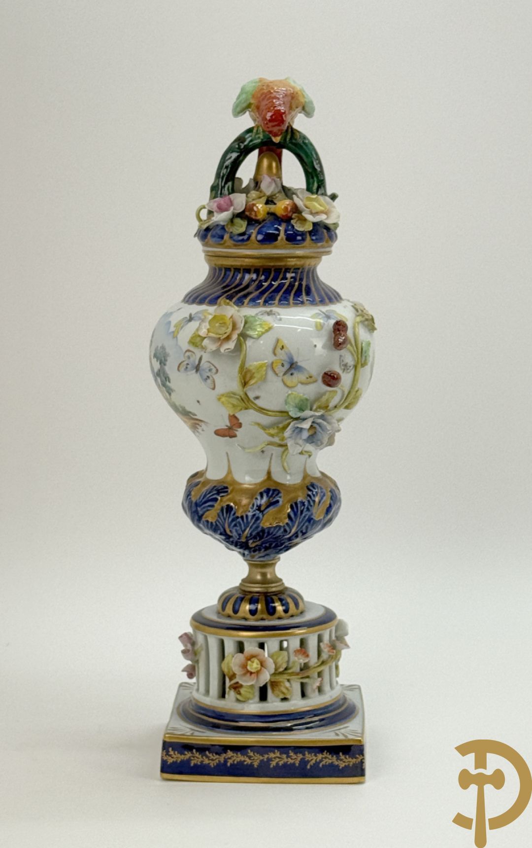 Porseleinen siervaas met handbeschilderd geanimeerd decor bezet met basrelief van bloemen en bovenaan bekroond met deksel met vogel