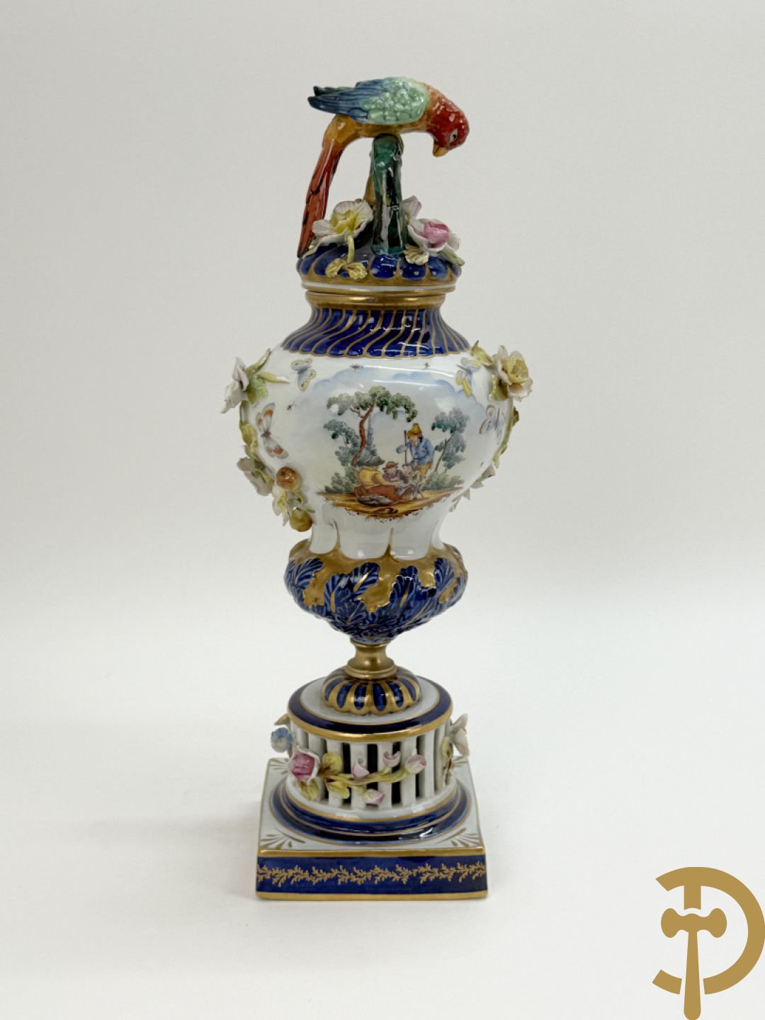 Porseleinen siervaas met handbeschilderd geanimeerd decor bezet met basrelief van bloemen en bovenaan bekroond met deksel met vogel