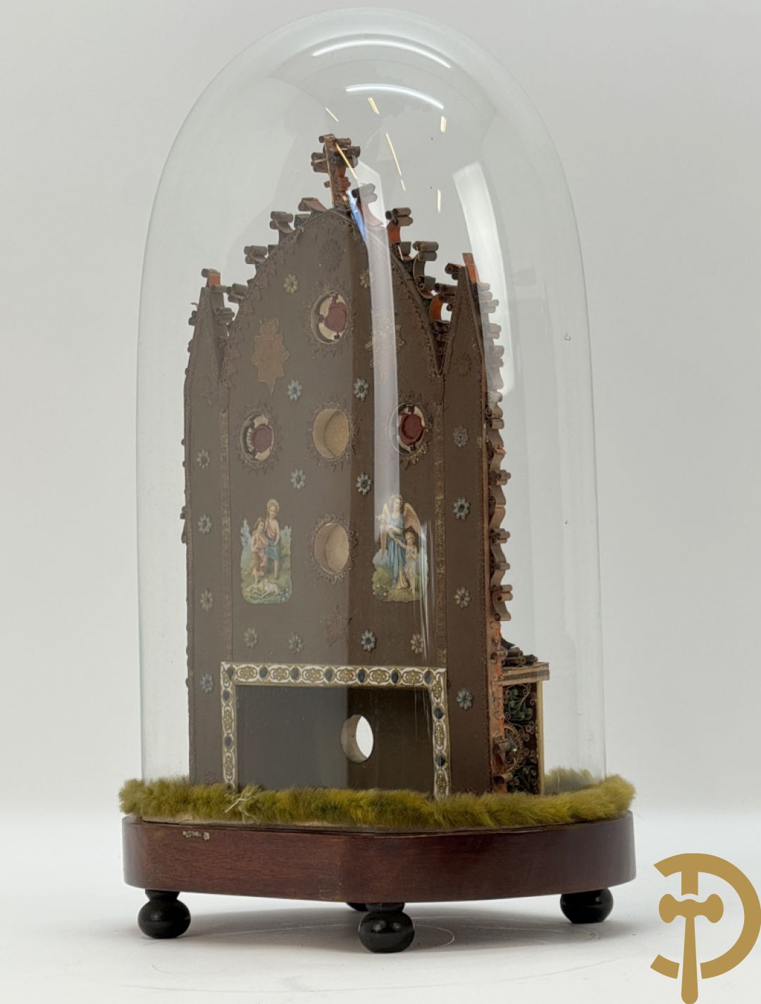 Relikwiehouder in de vorm van een altaar met Christusnagel en omgeven door papperollen - onder stolp