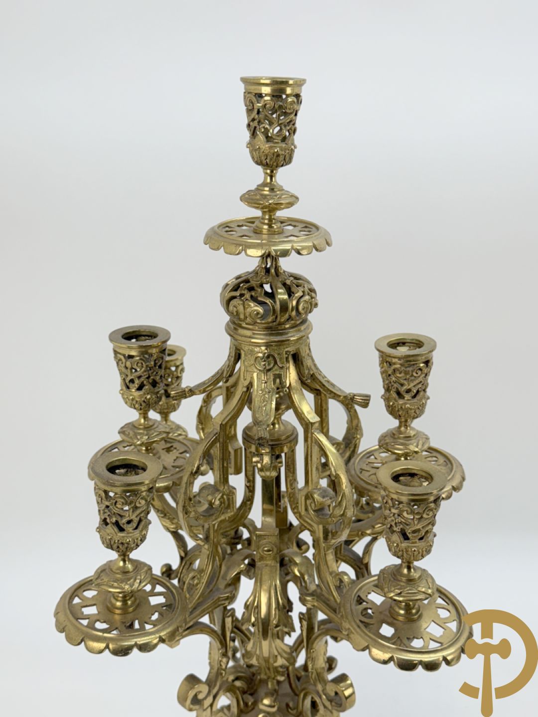 Driedelige bronzen vergulde garntiuur bestaande uit klok met medusahoofden en sfinxen, geflankeerd door paar zevenarmige kandelaars met accanthusranken en sfinxen