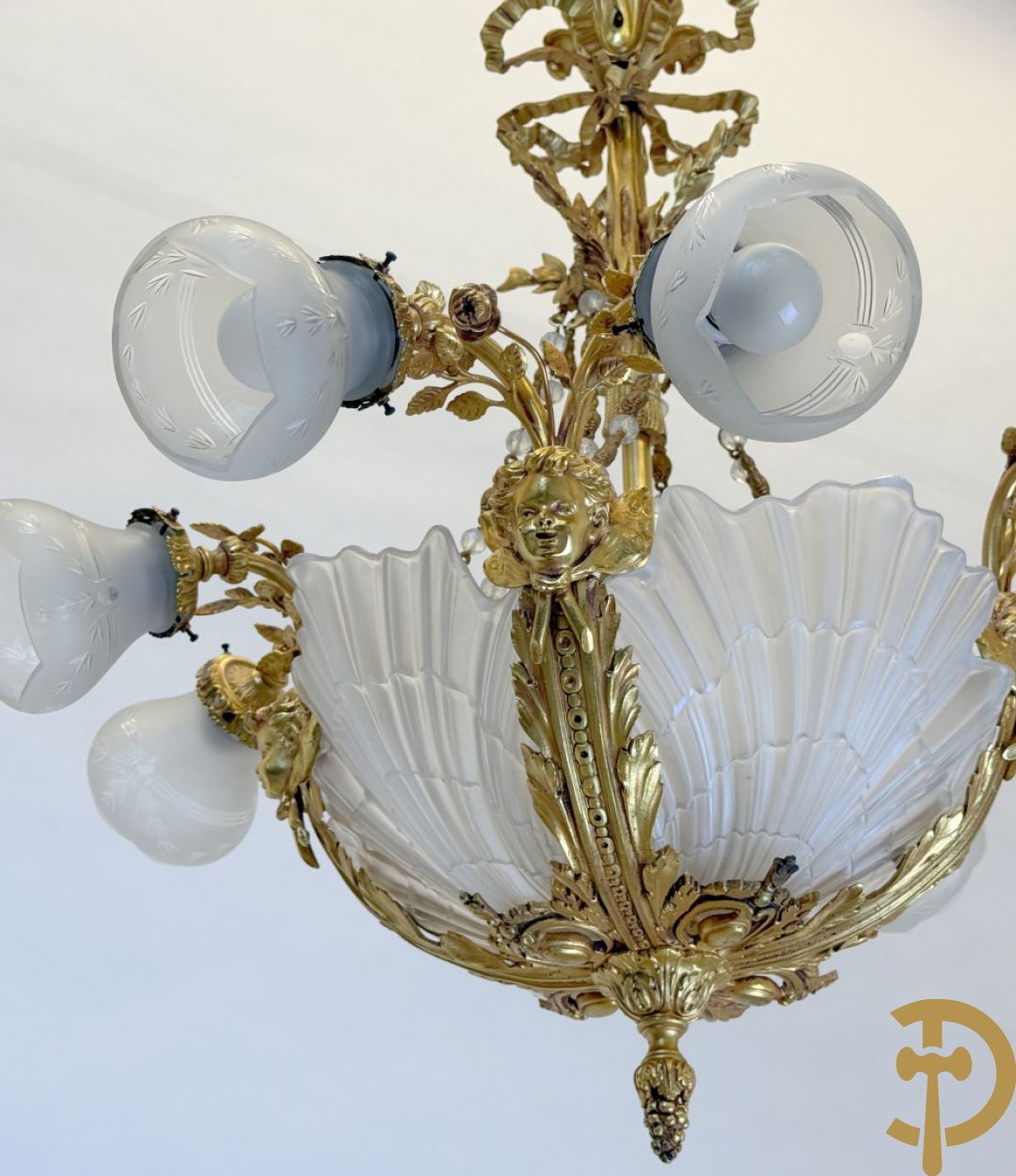 Bronzen vuurvergulde luchter met 4 paar lichtpunten bezet met bladranken, onderaan met glazen schelpen en armen bezet met cupidohoofden