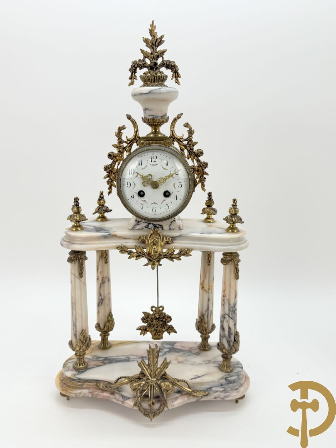 Driedelige wit marmeren garnituur bestaande uit vierzuilenpendule met bloemen en troffee geflankeerd door paar cassolettes met ramskoppen bezet