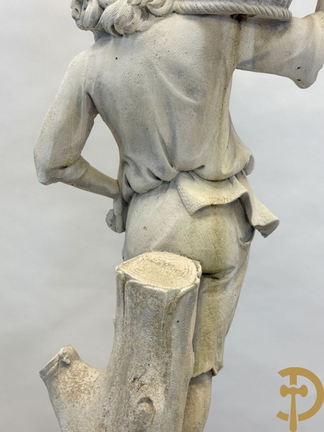 Stenen tuinbeeld van jongeman met mand in de hand op sokkel met guirlandes