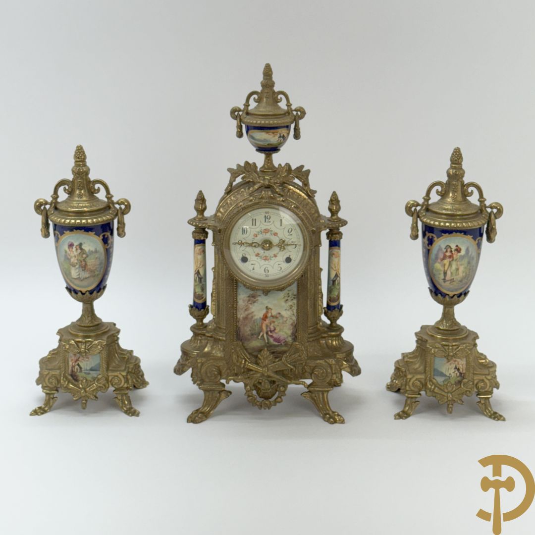 Driedelige koperen garnituur bestaande uit pendule met beschilderd romantisch tafereel en amfoor, zijdelings bezet met paar cassolettes met geanimeerde scènes, onleesbaar getekend rechts onder klok