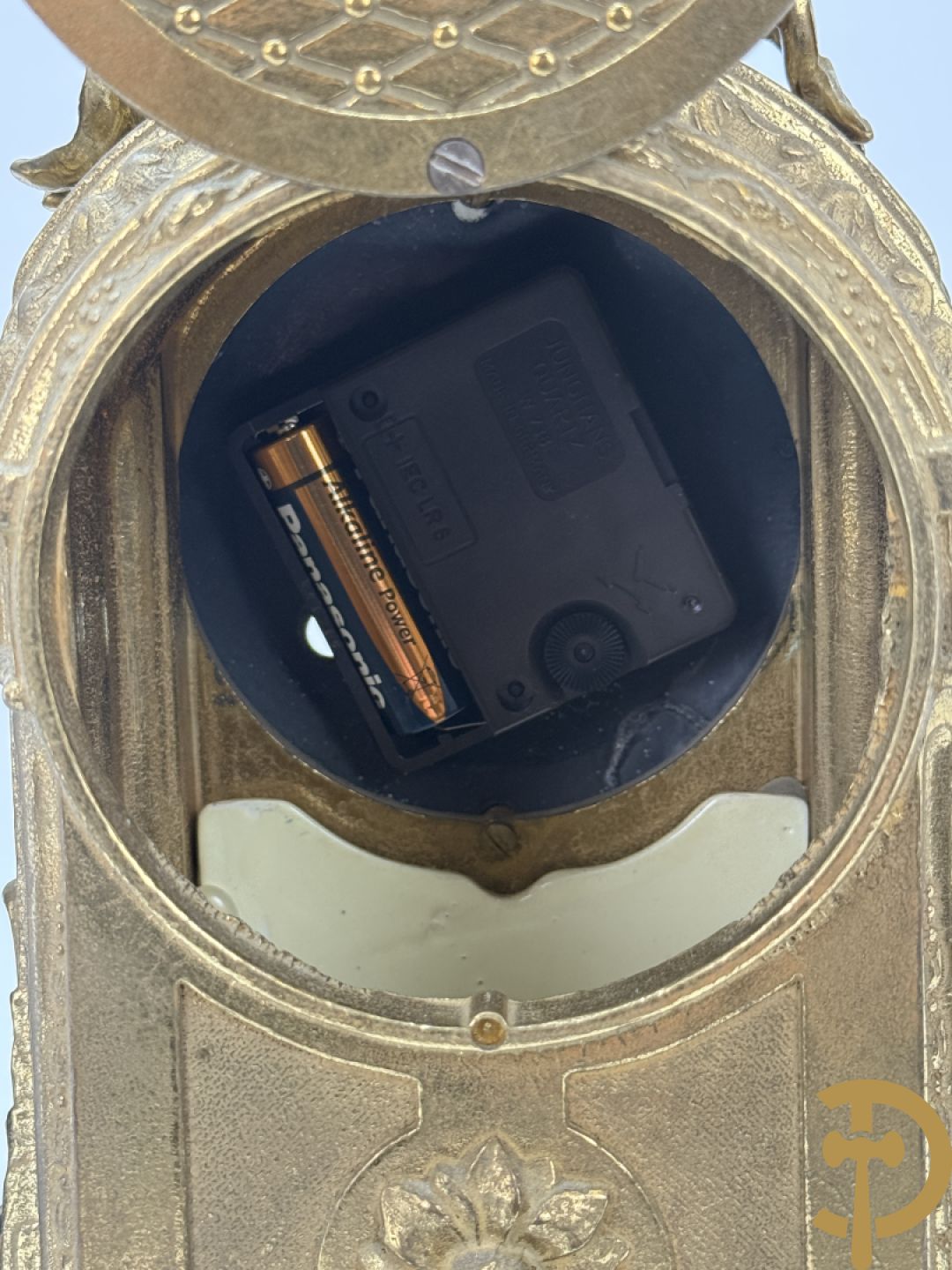 Driedelige koperen garnituur bestaande uit pendule met beschilderd romantisch tafereel en amfoor, zijdelings bezet met paar cassolettes met geanimeerde scènes, onleesbaar getekend rechts onder klok