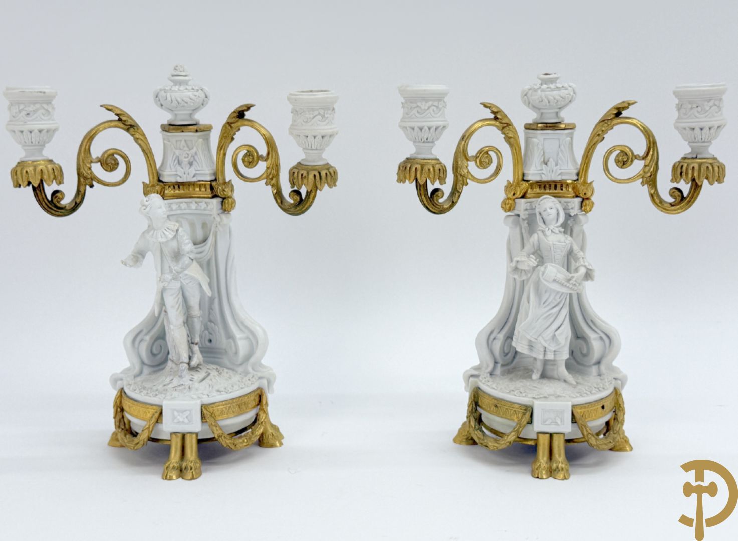 Driedelige porseleinen garnituur met bronsbeslag bestaande uit pendule met dame en amfoor geflankeerd door paar kandelaars bezet met personages