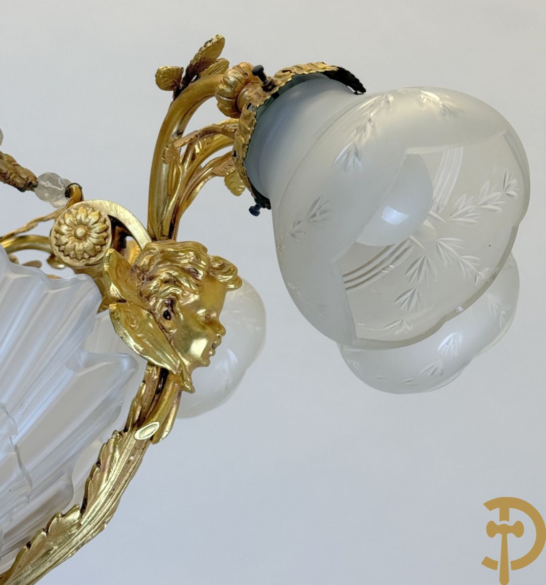 Bronzen vuurvergulde luchter met 4 paar lichtpunten bezet met bladranken, onderaan met glazen schelpen en armen bezet met cupidohoofden