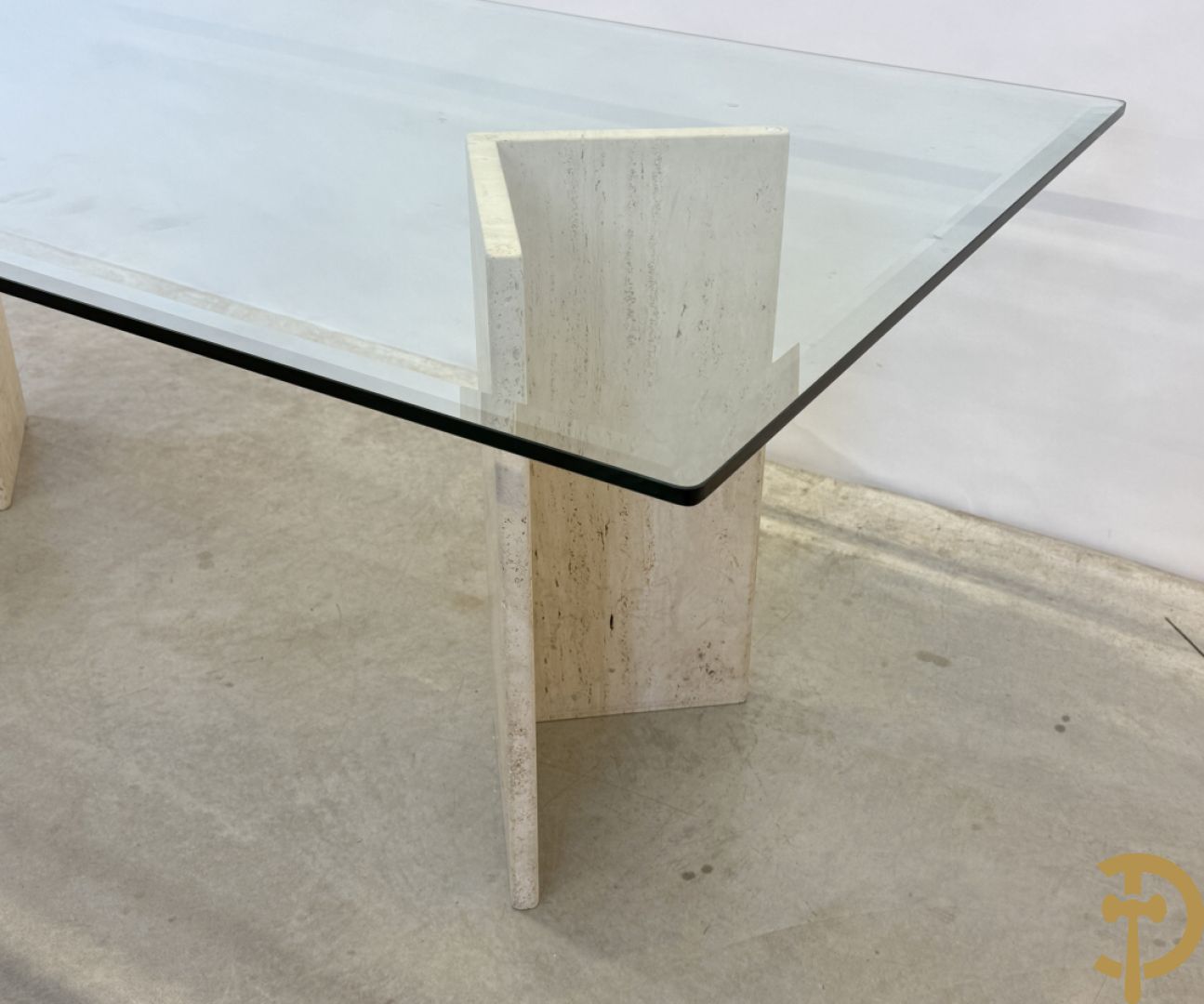 Moderne tafel met geslepen glazen blad op 2 travertin steunen