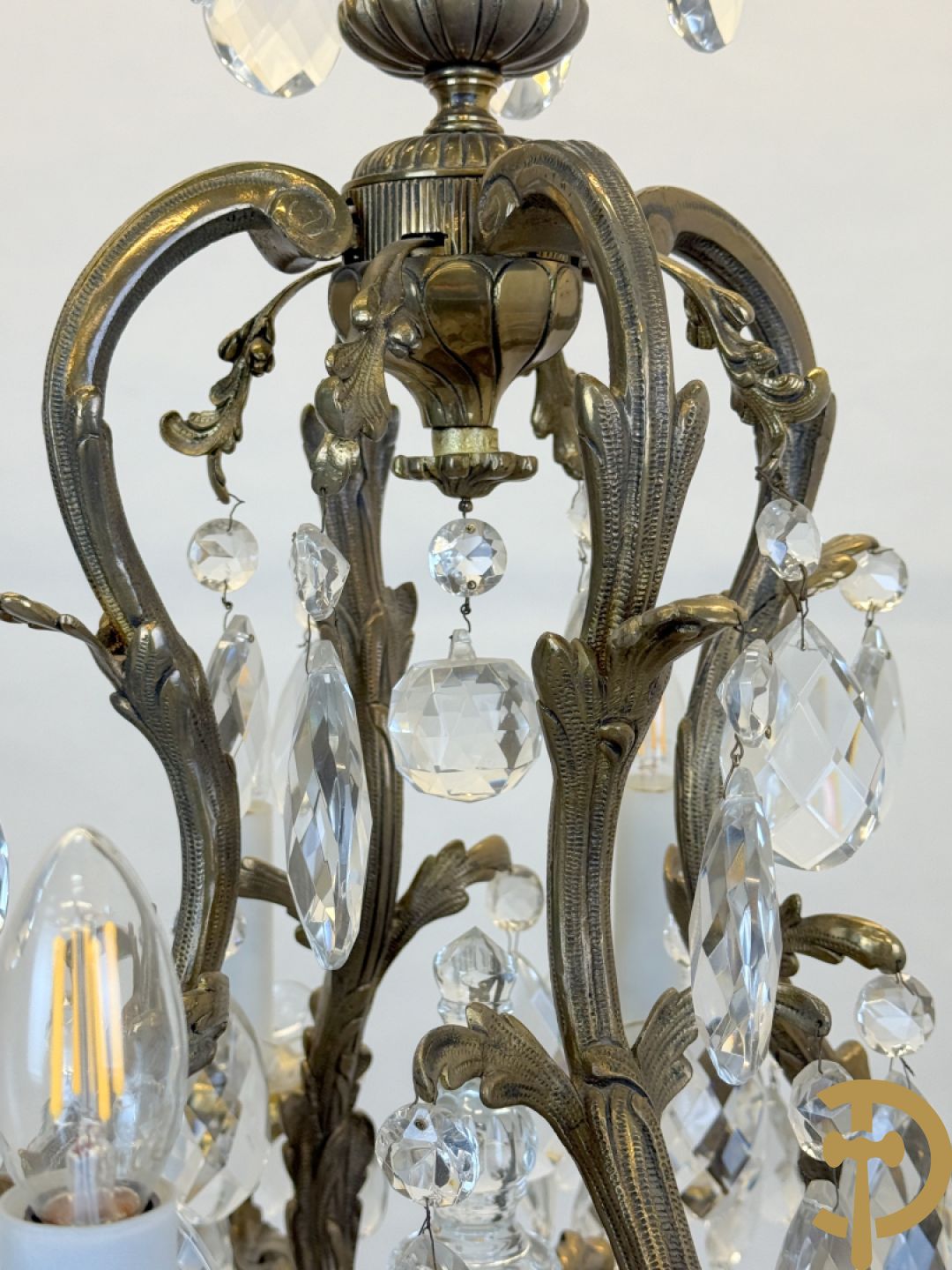 Achtarmige koperen luchter met kristallen bellen en binnenin met pinakel bezet