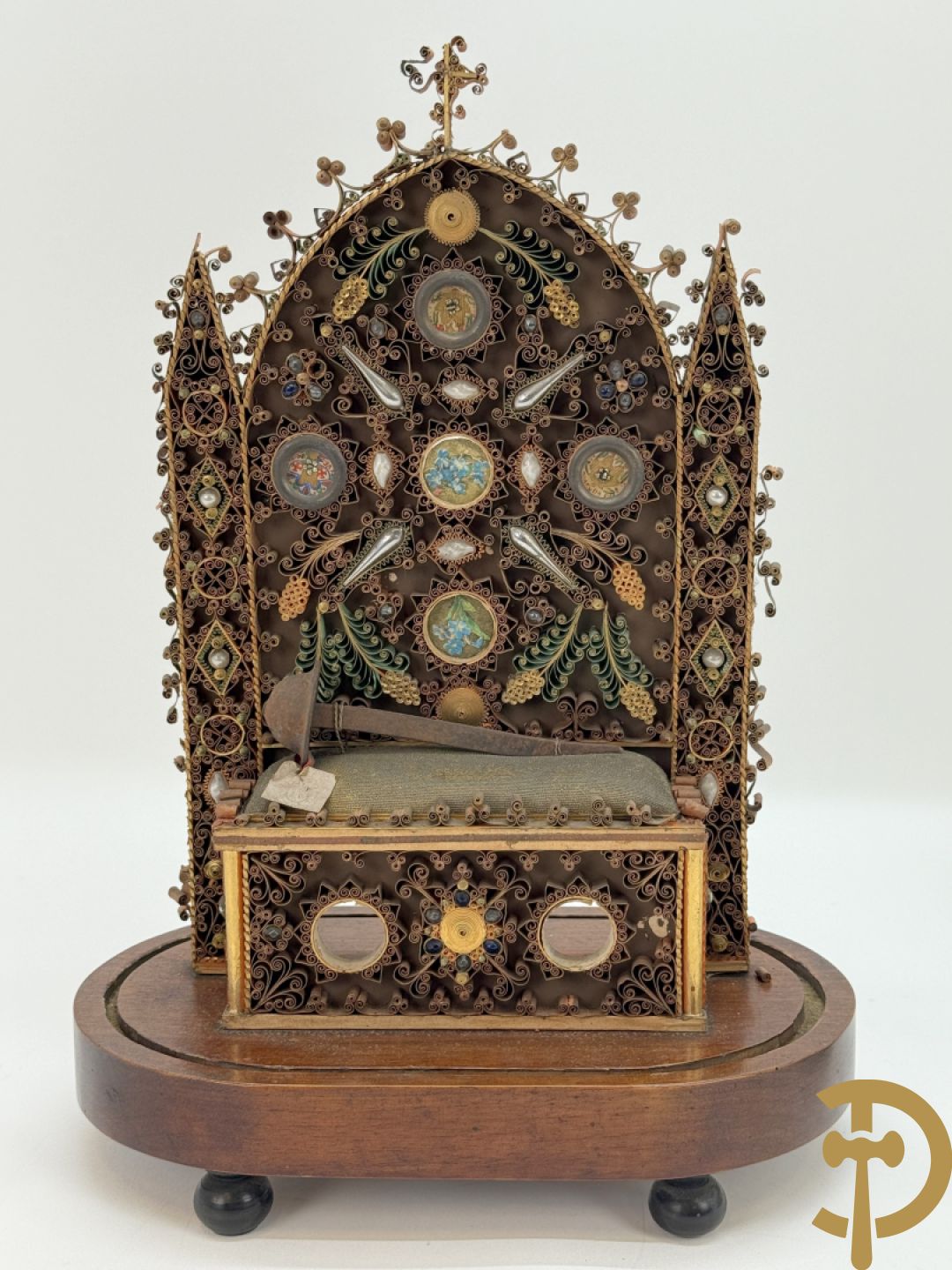 Relikwiehouder in de vorm van een altaar met Christusnagel en omgeven door papperollen - onder stolp