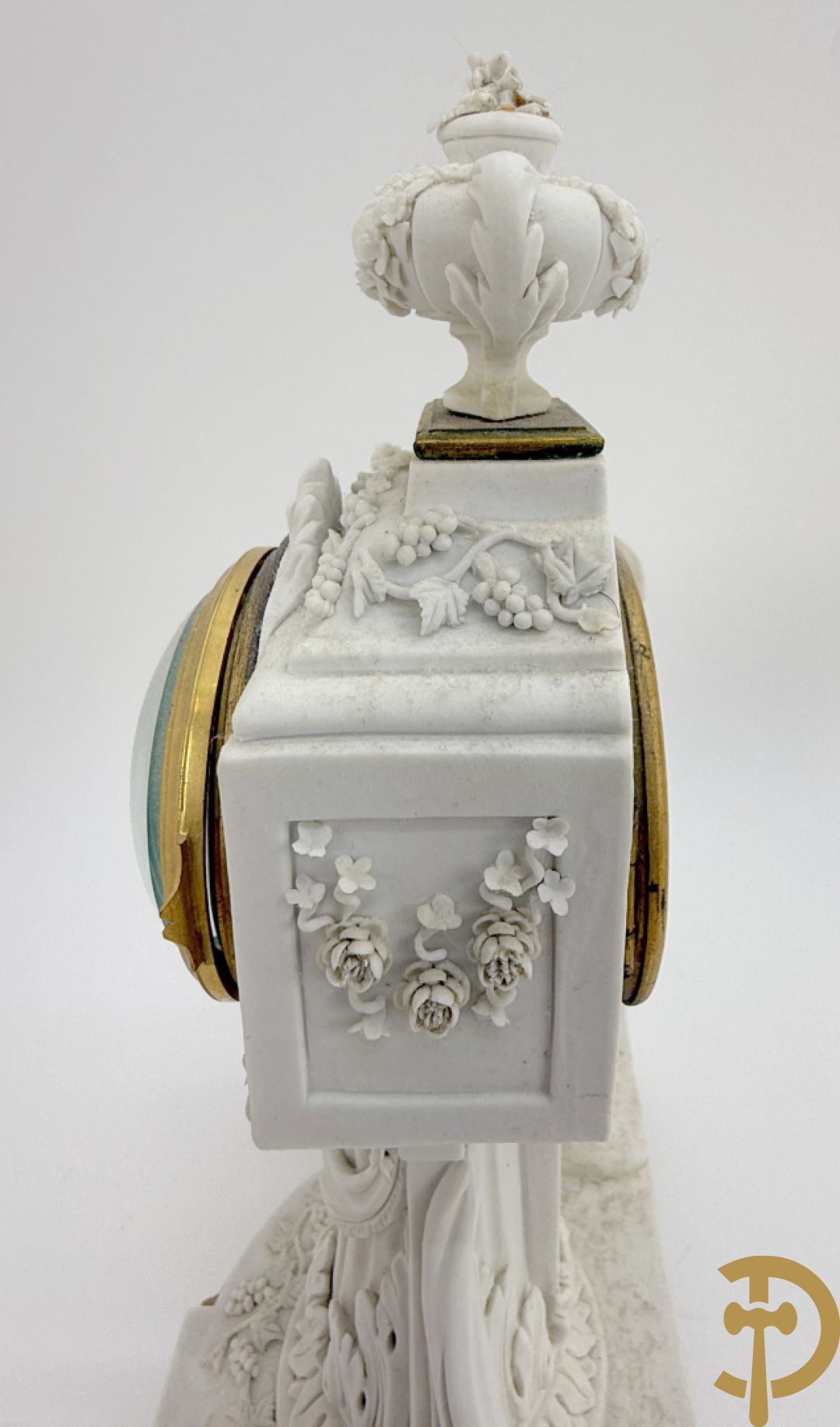 Driedelige porseleinen garnituur met bronsbeslag bestaande uit pendule met dame en amfoor geflankeerd door paar kandelaars bezet met personages