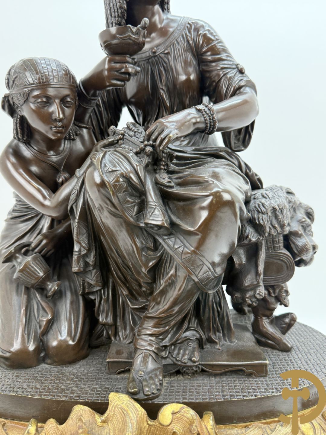 Driedelige bronzen garnituur bestaande uit middenstuk met bronzen vuurvergulde klok, Daubrée gemerkt à Nancy, bovenaan bekroond met Cleopatra met drinkbeker - getekend van Cumberworth sculpteur - geflankeerd door paar cupido