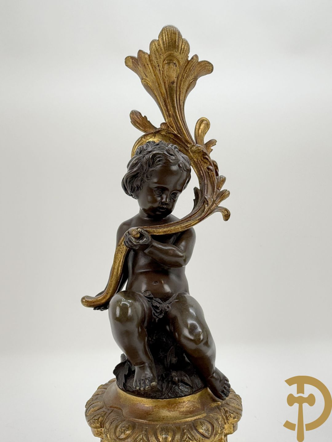 Driedelige bronzen garnituur bestaande uit middenstuk met bronzen vuurvergulde klok, Daubrée gemerkt à Nancy, bovenaan bekroond met Cleopatra met drinkbeker - getekend van Cumberworth sculpteur - geflankeerd door paar cupido