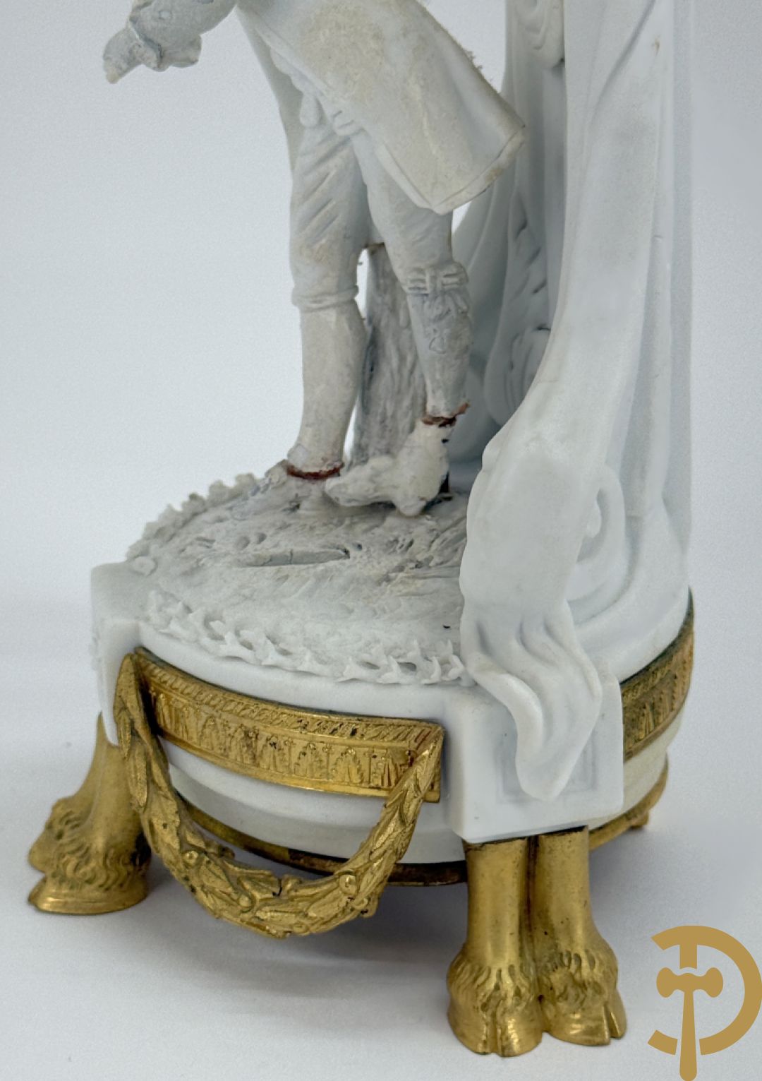 Driedelige porseleinen garnituur met bronsbeslag bestaande uit pendule met dame en amfoor geflankeerd door paar kandelaars bezet met personages