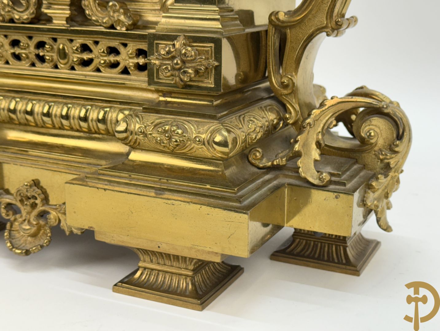 Vuurvergulde bronzen pendule, zijdelings bezet met gevleugelde dames, bovenaan met amfoor