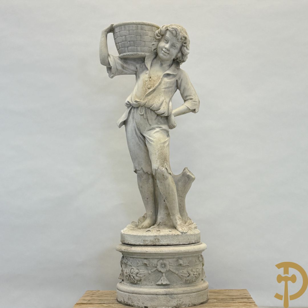 Stenen tuinbeeld van jongeman met mand in de hand op sokkel met guirlandes