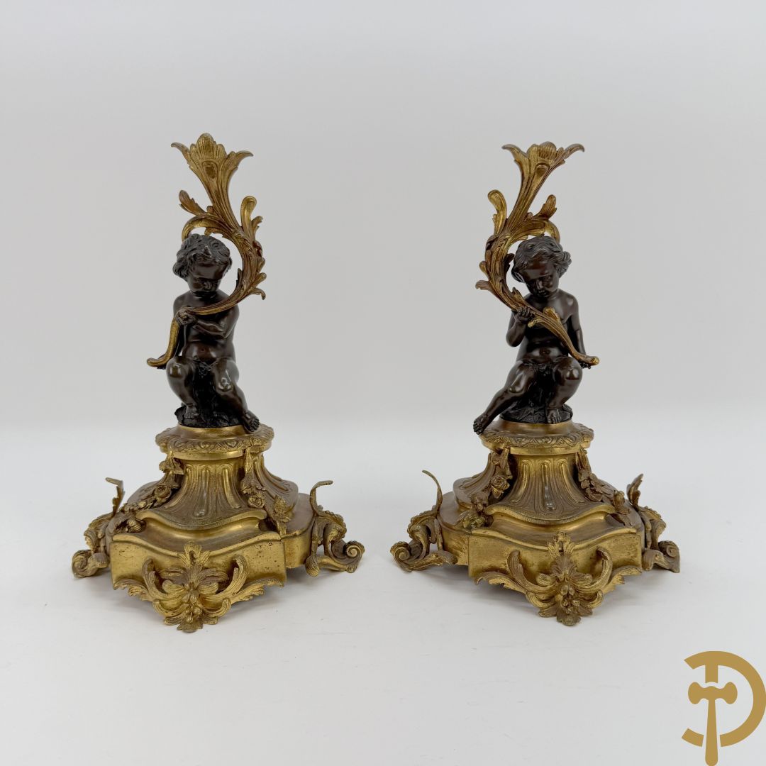 Driedelige bronzen garnituur bestaande uit middenstuk met bronzen vuurvergulde klok, Daubrée gemerkt à Nancy, bovenaan bekroond met Cleopatra met drinkbeker - getekend van Cumberworth sculpteur - geflankeerd door paar cupido