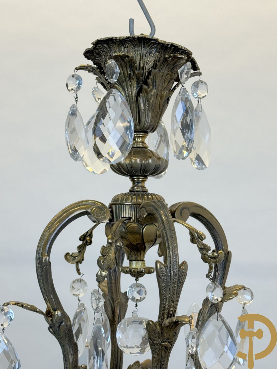 Achtarmige koperen luchter met kristallen bellen en binnenin met pinakel bezet