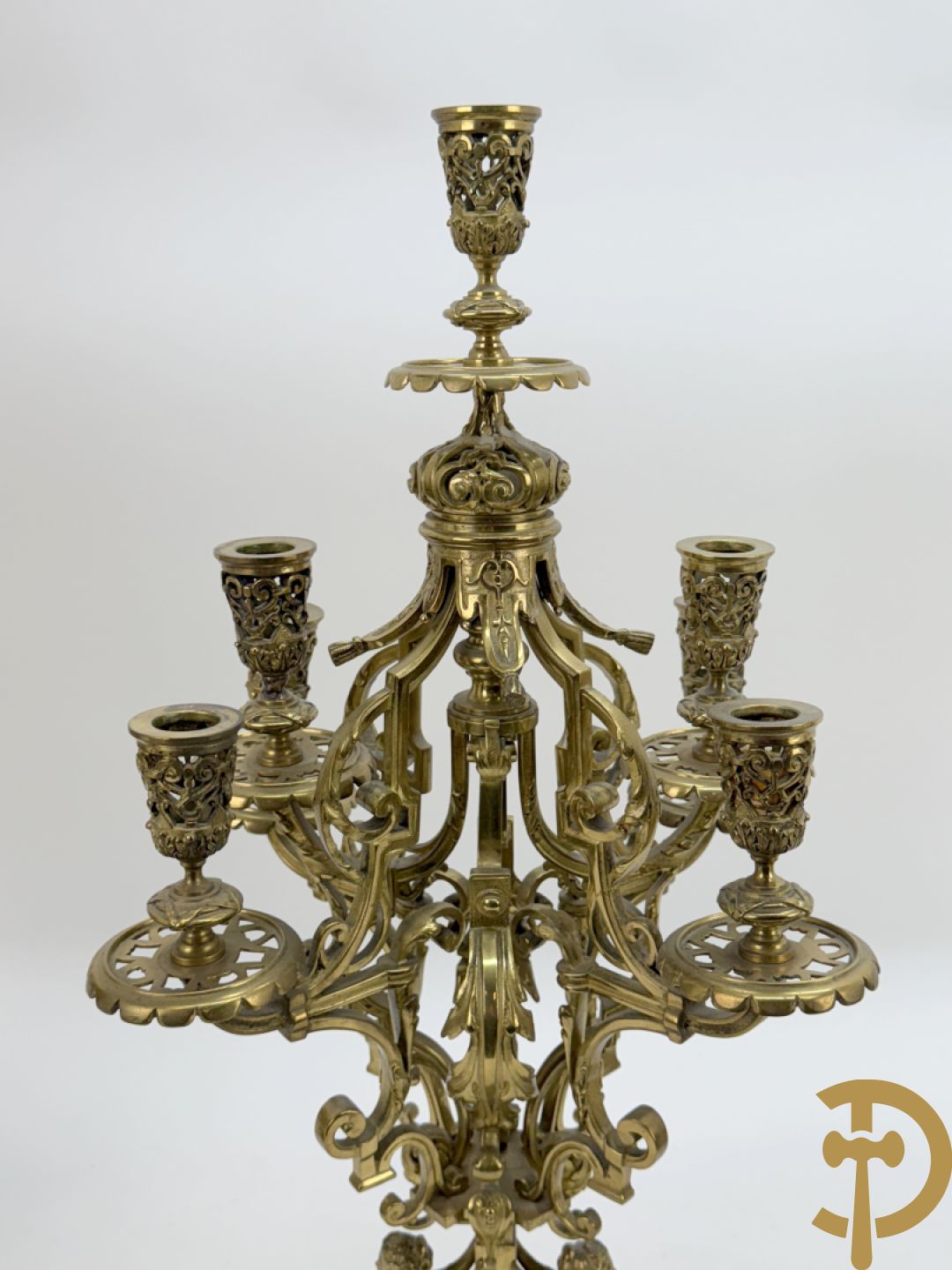 Driedelige bronzen vergulde garntiuur bestaande uit klok met medusahoofden en sfinxen, geflankeerd door paar zevenarmige kandelaars met accanthusranken en sfinxen