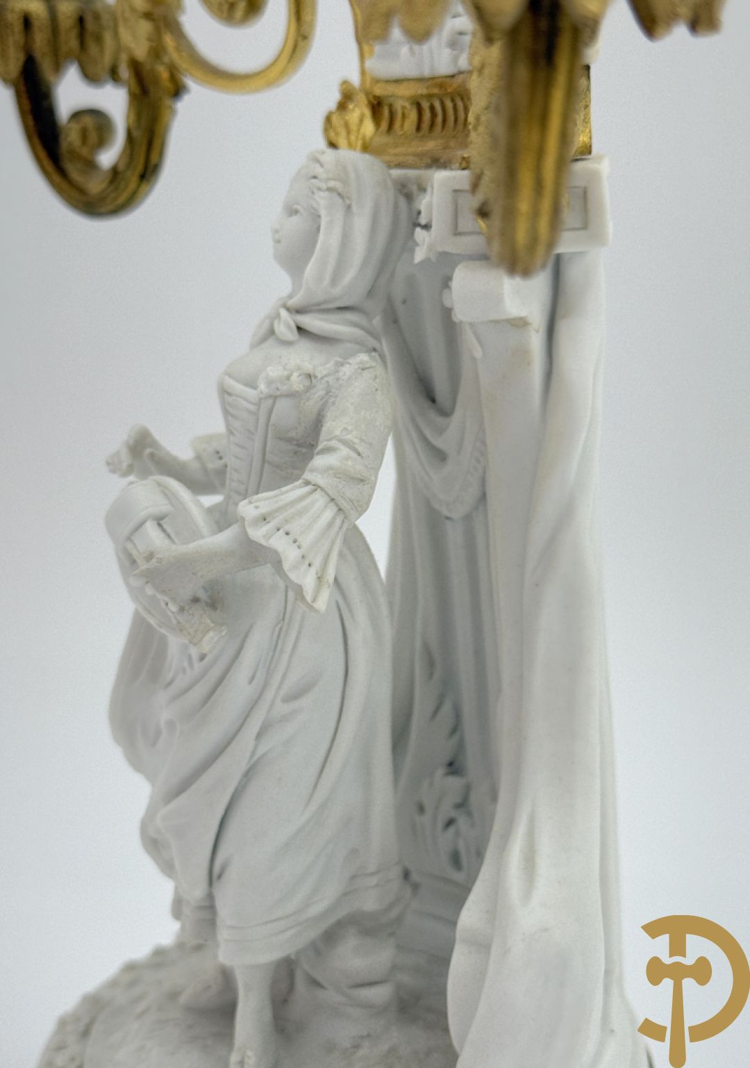 Driedelige porseleinen garnituur met bronsbeslag bestaande uit pendule met dame en amfoor geflankeerd door paar kandelaars bezet met personages