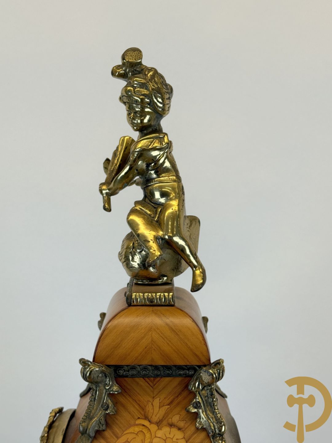 Notelaren pendule met bloemenmarquetterie en bronsbeslag, bovenaan bekroond met bronzen figuur - met bijhorende sokkel in notelaar met bronsbeslag