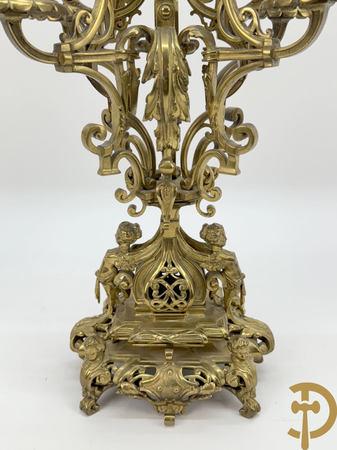 Driedelige bronzen vergulde garntiuur bestaande uit klok met medusahoofden en sfinxen, geflankeerd door paar zevenarmige kandelaars met accanthusranken en sfinxen