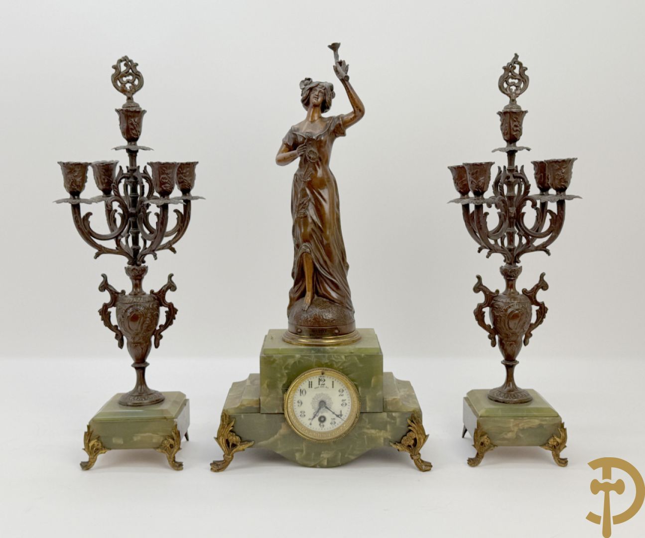 Driedelige zamak garnituur met dame Pavot met bloemen op uurwerk, Rucho getekend, geflankeerd door paar kandelaars