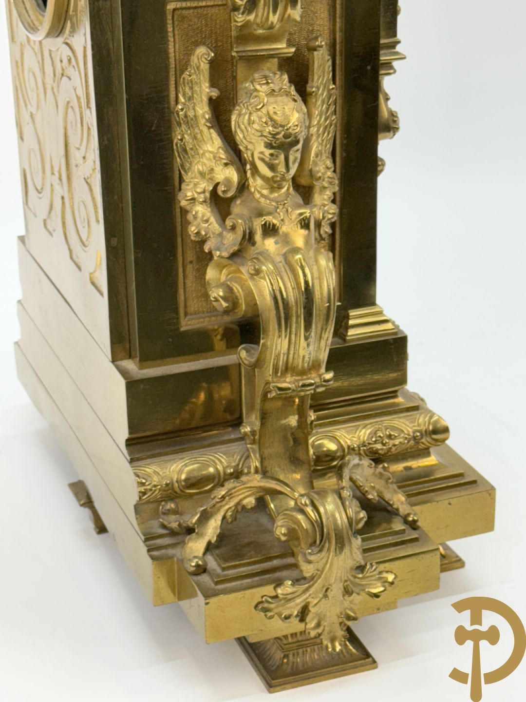 Vuurvergulde bronzen pendule, zijdelings bezet met gevleugelde dames, bovenaan met amfoor