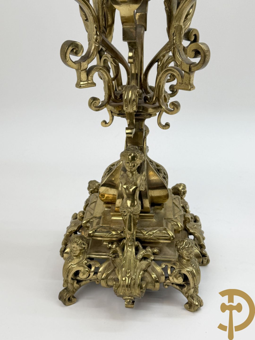 Driedelige bronzen vergulde garntiuur bestaande uit klok met medusahoofden en sfinxen, geflankeerd door paar zevenarmige kandelaars met accanthusranken en sfinxen