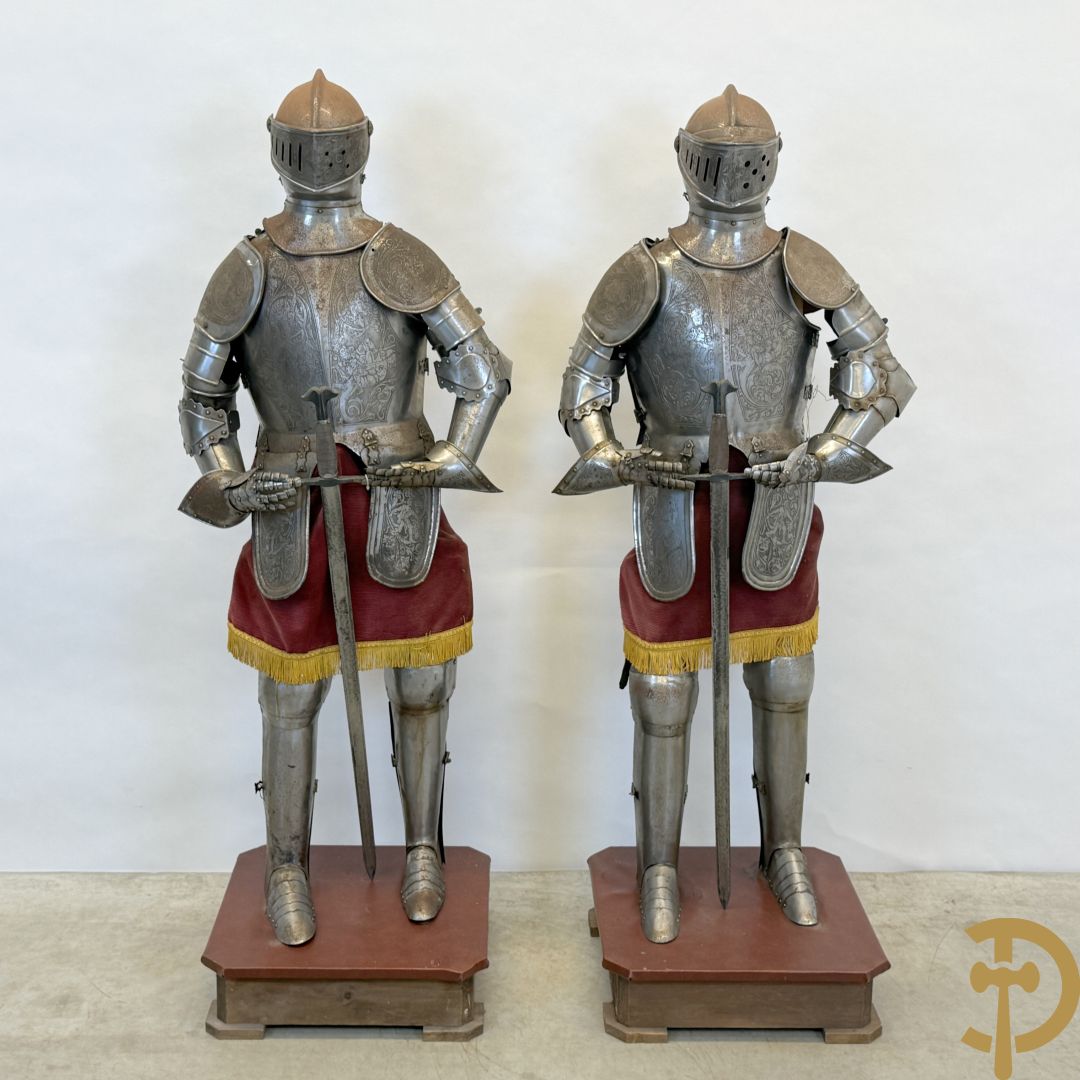 Paar ijzeren decoratieve harnassen ridderuitrusting met geciseleerde motieven op de elementen, met zwaard en ridderhelm - op statief - vermoedelijk Spaans 1930-1940