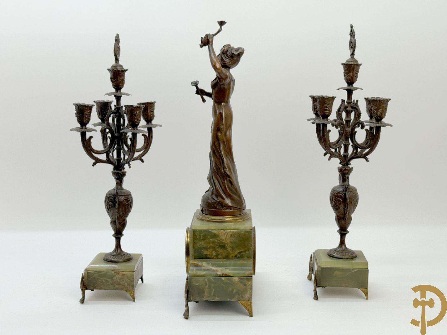 Driedelige zamak garnituur met dame Pavot met bloemen op uurwerk, Rucho getekend, geflankeerd door paar kandelaars